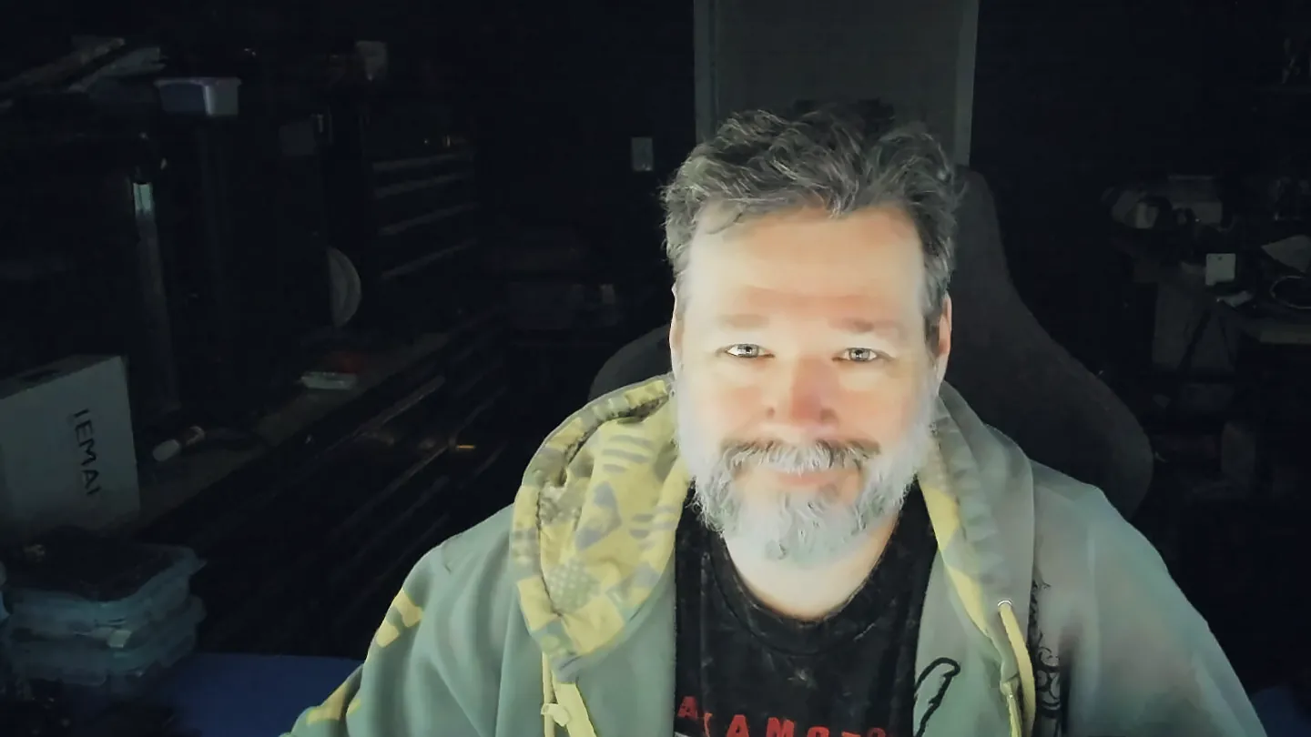 Chris Watkins at his desk in his workshop, smiling at the camera
